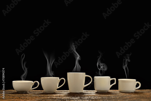Variety of cups of coffee with smoke on black background
