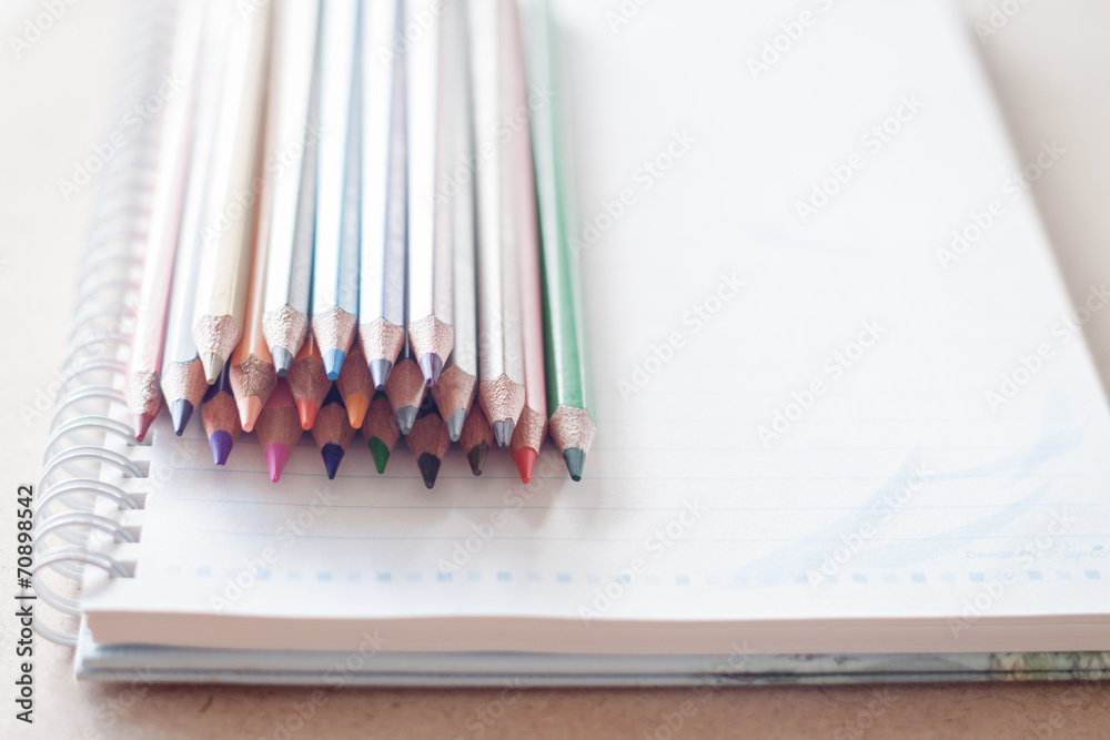 Cluster of colorful pencil crayons on spiral notebook Cluster of colorful pencil crayons on spiral notebook