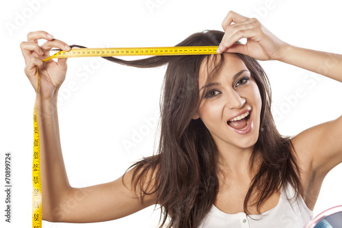 Happy attractive girl measured her hair with a tape measure