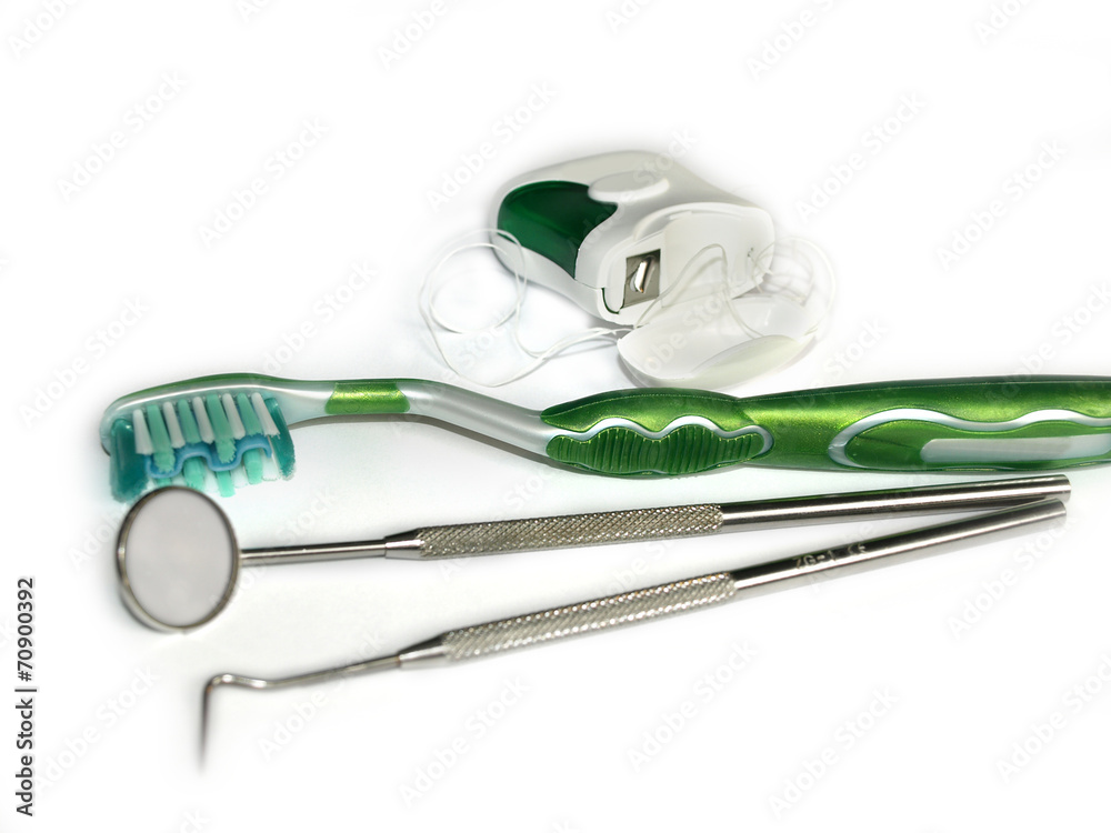Toothbrushes, dental floss and a mirror on white
