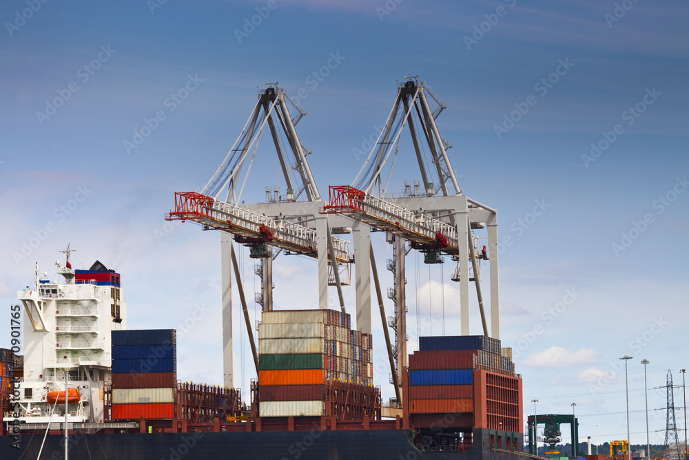 Container ship in a harbor with cranes moving cargo