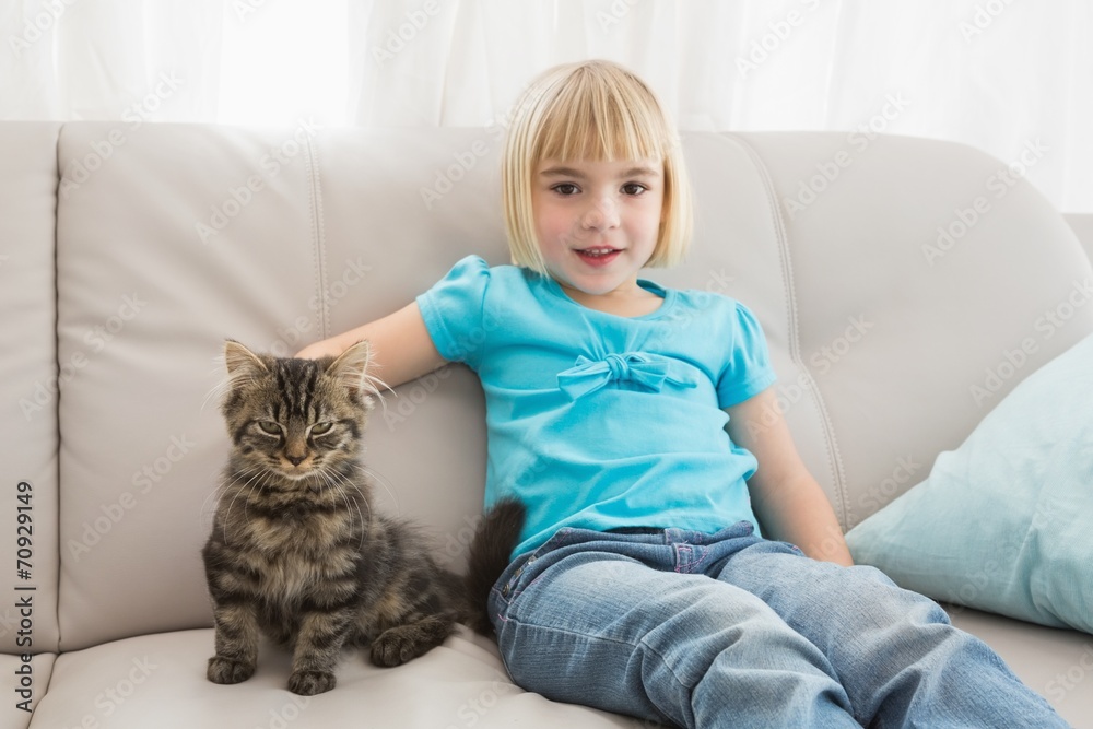 Little girl sitting on the couch stroking her cat Little girl sitting on the couch stroking her cat