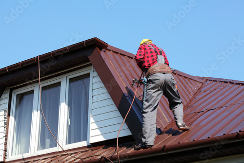 roofer builder worker spraying paint on roof