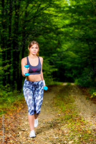 Beautiful young woman doing stretching exercise on road forest