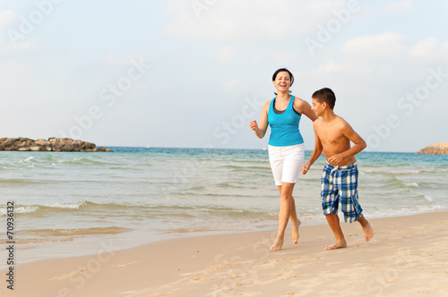 Mother with her son are running on the beach and having fun