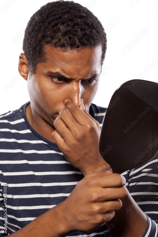 nervous dark-skinned young man touching his nose in the mirror Stock Photo  | Adobe Stock