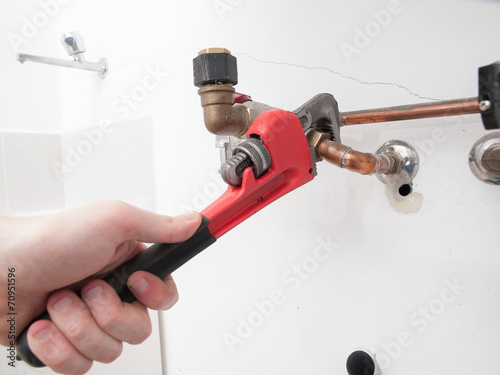 Hands repairing the plumbing pipes of an electric boiler