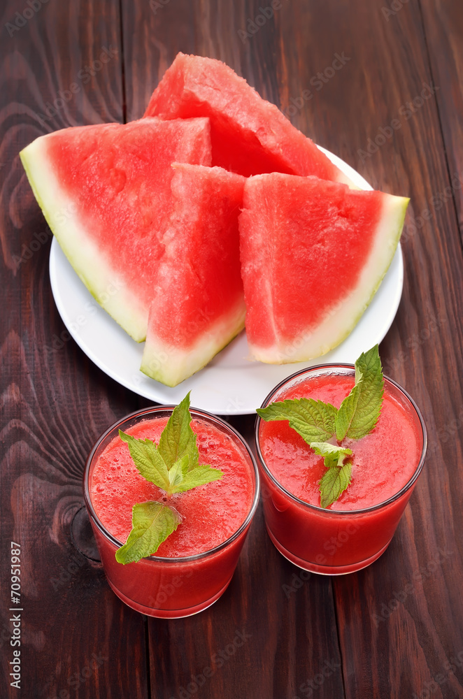 Watermelon cocktail and slices on wooden table
