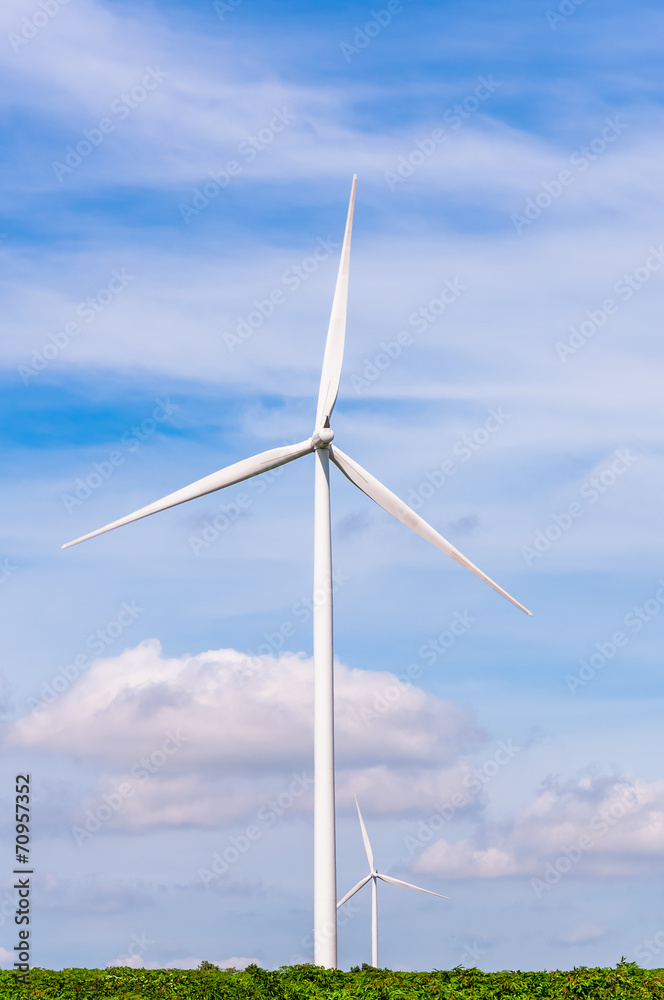 Wind turbine on the green meadow over the blue clouded sky Wind turbine on the green meadow over the blue clouded sky