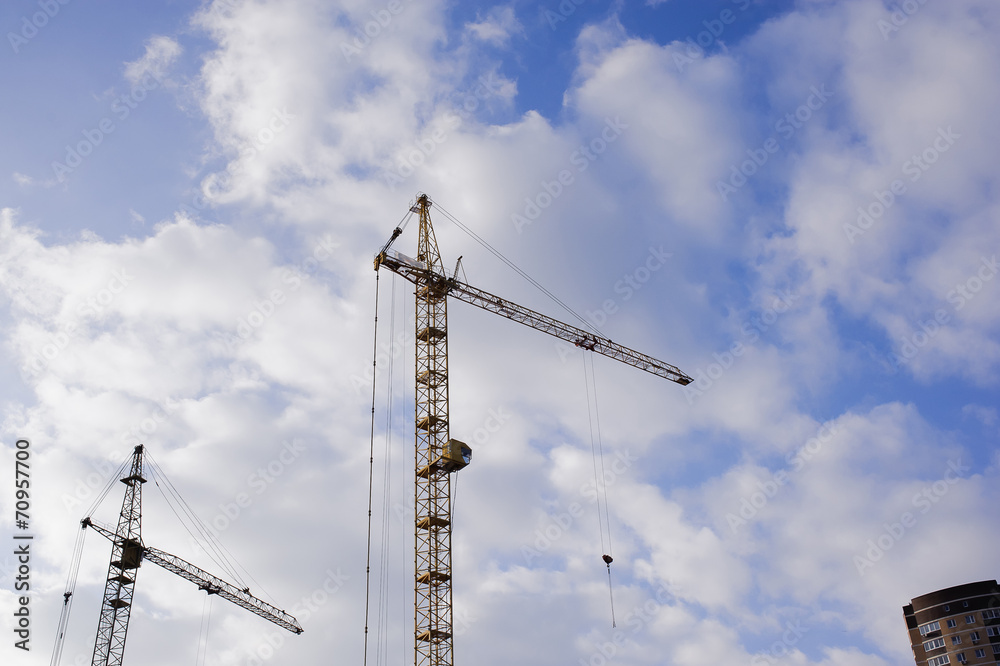 Two construction cranes against a background of blue sky Two construction cranes against a background of blue sky