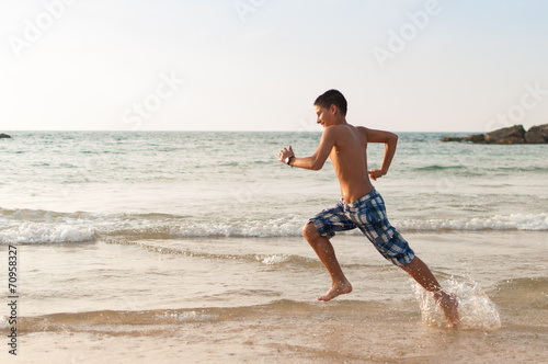 Teen boy is running along the beach