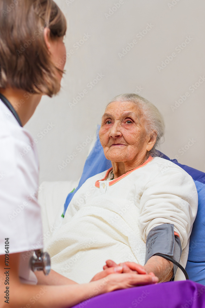 young nurse caregiving an old lady lying in bed
