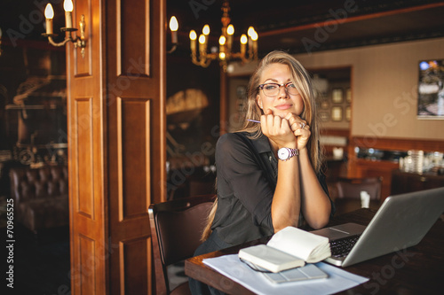 Business woman in glasses with laptop dreams in restaurant