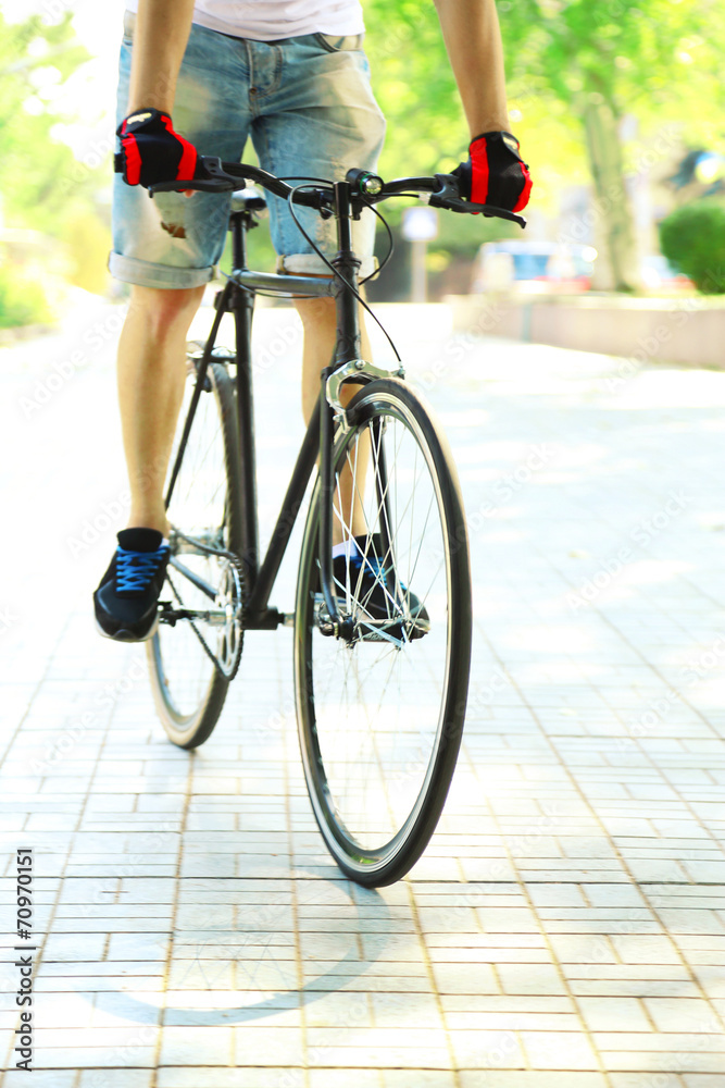 Naklejka premium Young man riding bike in city park
