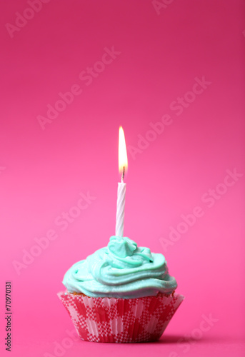 Delicious birthday cupcake on table on pink background