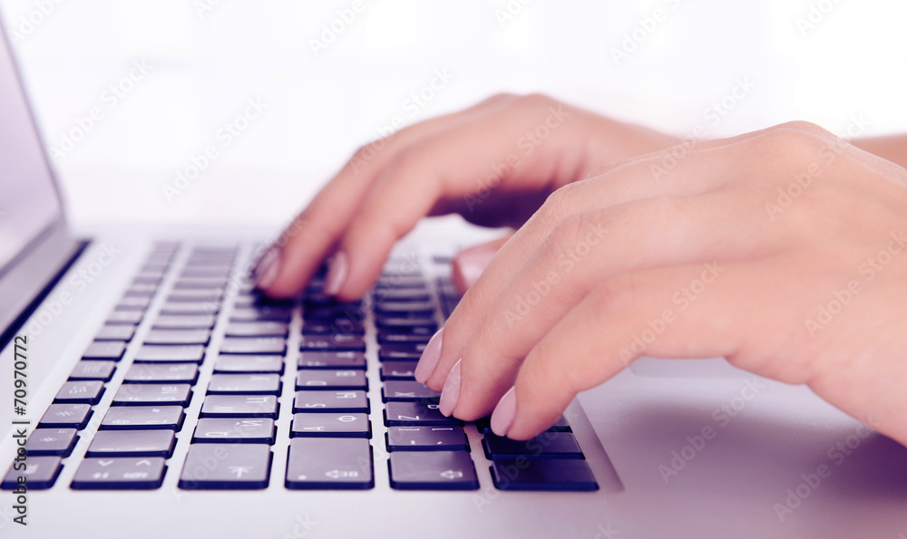 Female hands working on laptop on light background Female hands working on laptop on light background