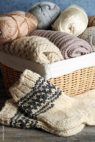 Knitting yarn in basket and socks, on wooden background