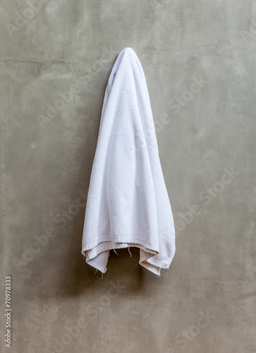 White towel is hanging on the exposed concrete wall in the bathr