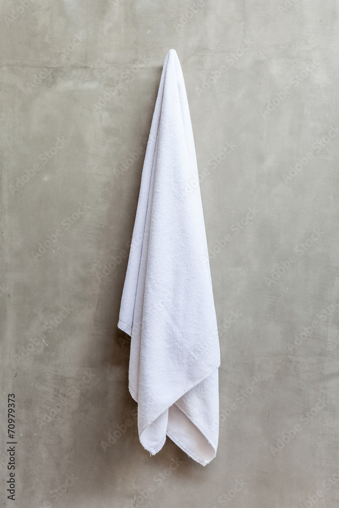 Obraz premium Hanging white towel draped on exposed concrete wall in the bathr