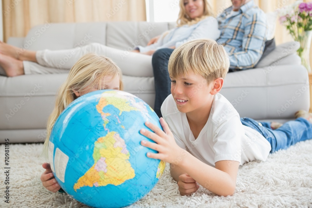 Siblings looking at globe on the floor Siblings looking at globe on the floor