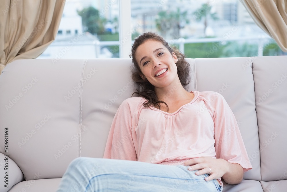 Pretty brunette smiling at camera on the couch Pretty brunette smiling at camera on the couch
