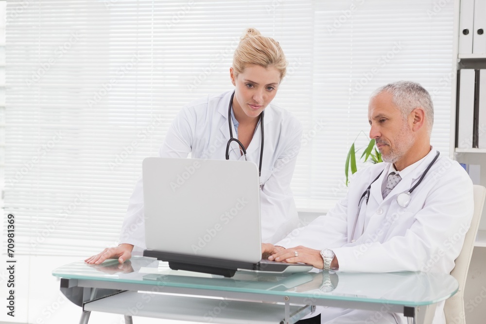 Concentrated doctors coworker using laptop Concentrated doctors coworker using laptop