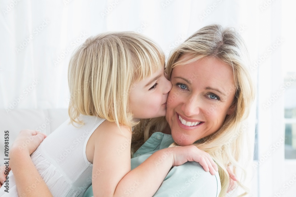 Mother sitting on the couch with her daughter kissing her cheek