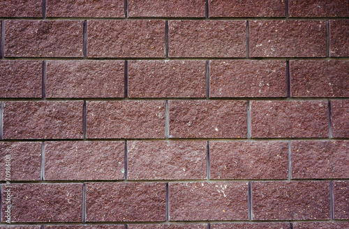 The wall of the large cherry-colored rectangular stones as backg