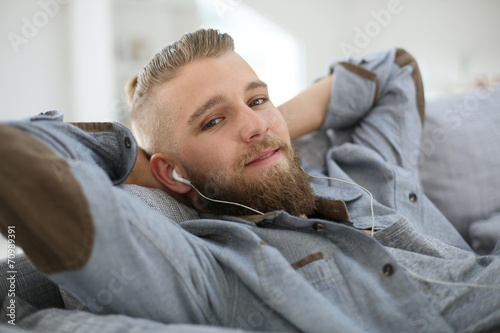 Young man relaxing in sofa, listening to music