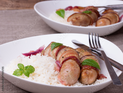 grilled bavarian sausages with rice and mint on white dish