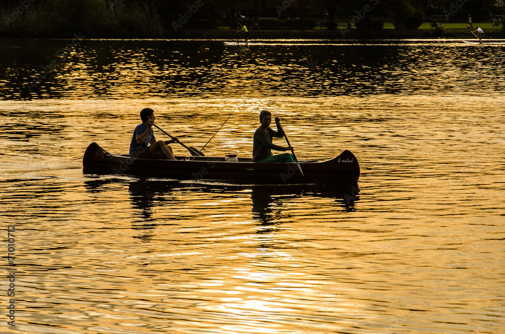 zwei junge Maenner paddeln bei Sonnenuntergang