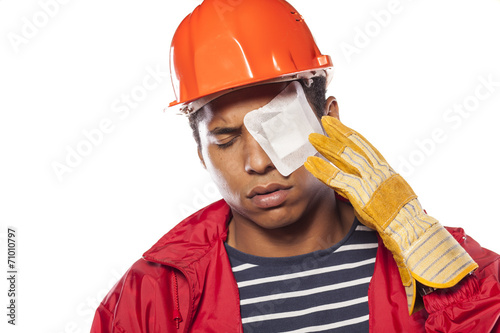 Tablou canvas sad dark-skinned worker with helmet and injured eye