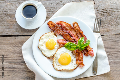 Fried eggs with bacon on the wooden table