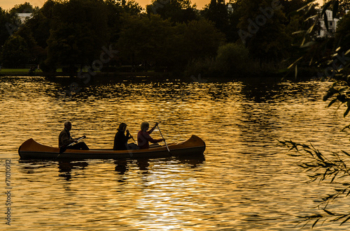 Frau und Maenner paddeln bei Sonnenuntergang © dietwalther