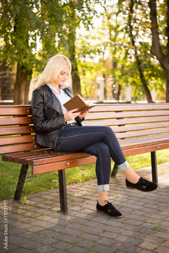 beautiful girl sitting on a bench and reading a book
