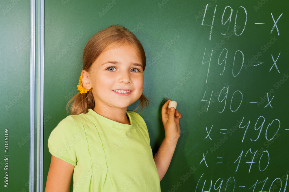 Cute girl with chalk in hand near blackboard