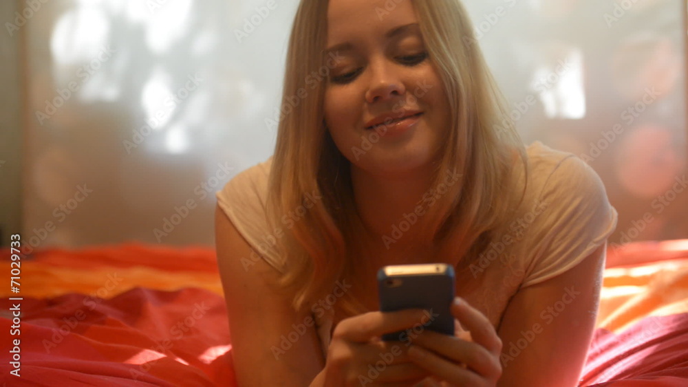 smiling blond girl writing message touch phone sms