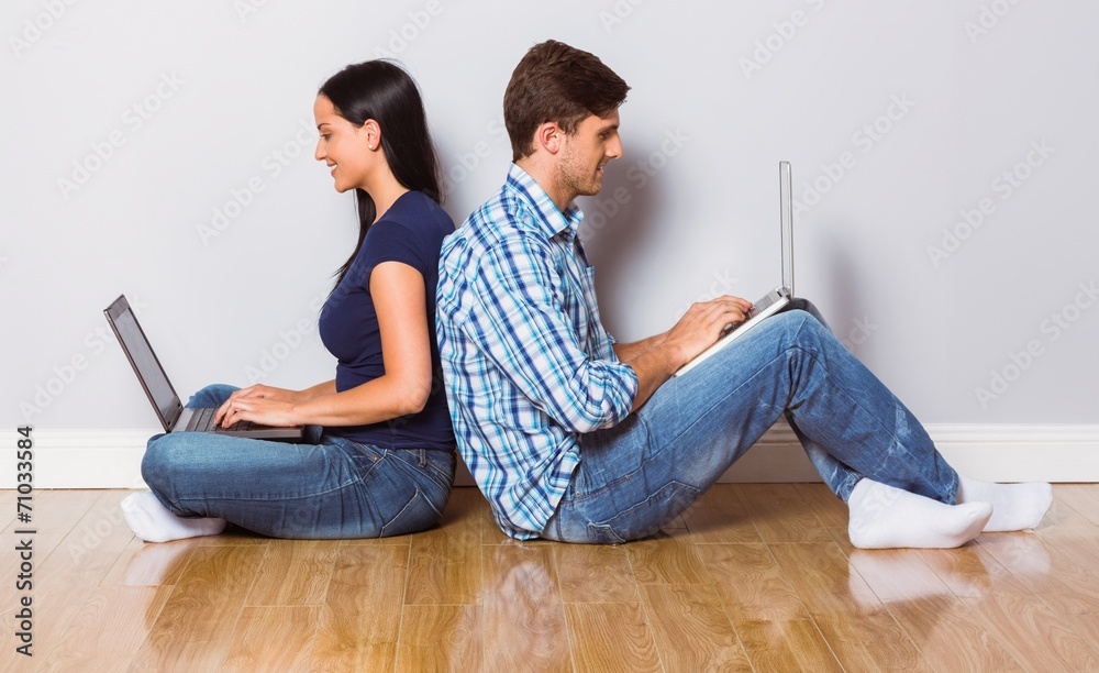 Young couple sitting on floor using laptop Young couple sitting on floor using laptop