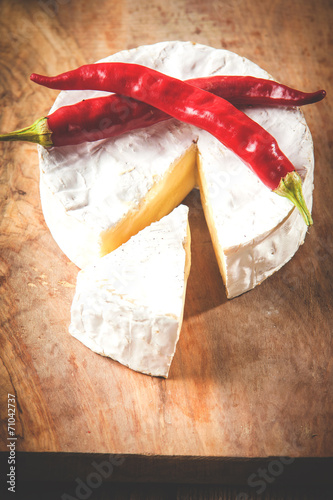 Smelly camembert cheese on a wooden rustic table with chili pepp photo