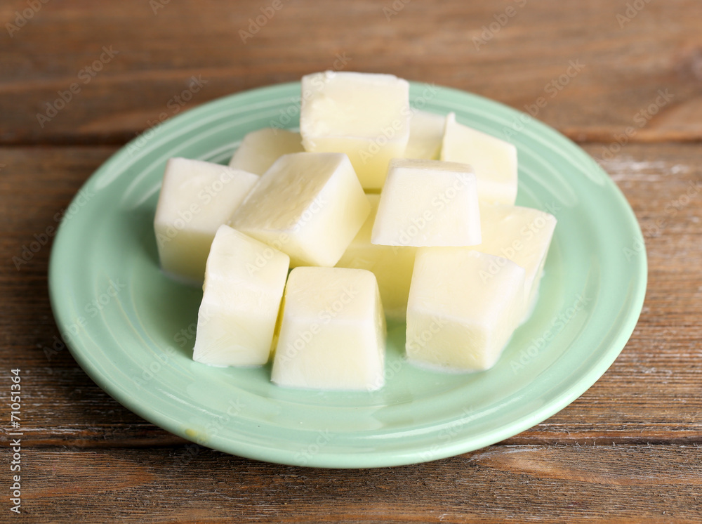 Milk ice cubes on plate on wooden background Milk ice cubes on plate on wooden background