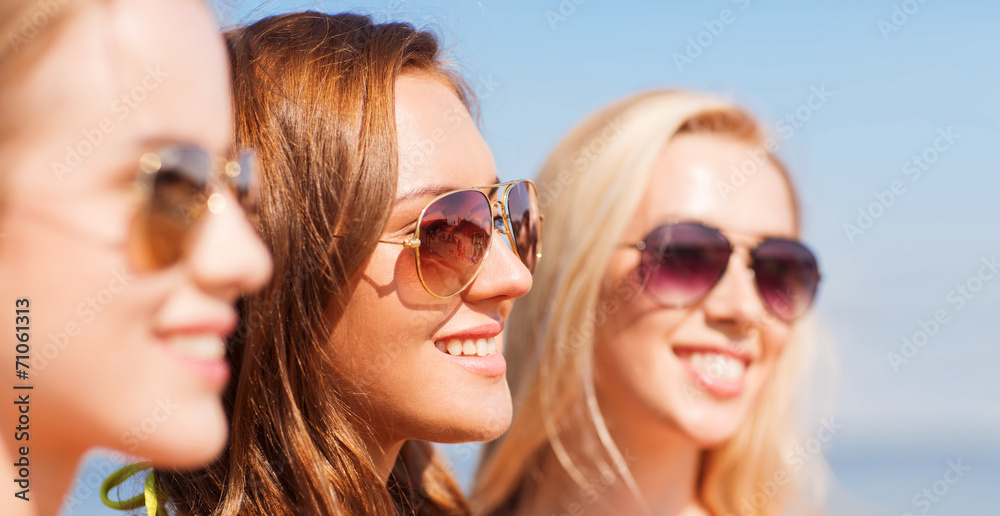 close up of smiling young women in sunglasses