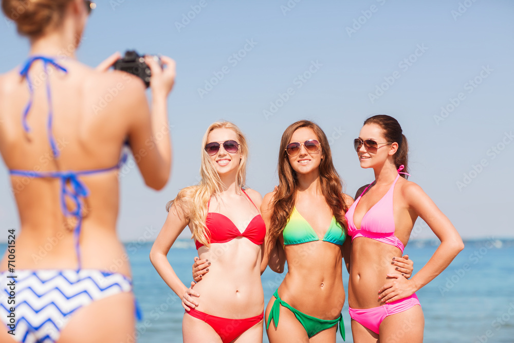 group of smiling women photographing on beach