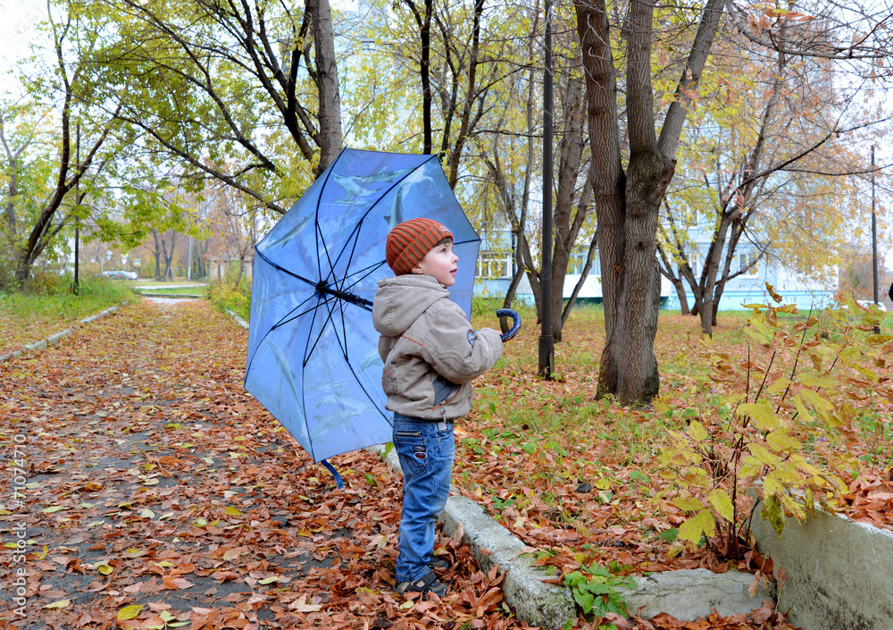 boy with blue umbrella in the autumn park