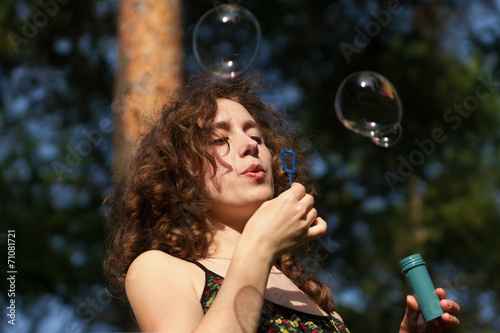 Young pretty woman blowing soap bubbles