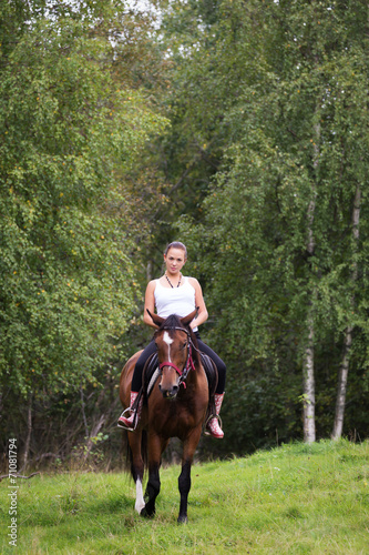 Elegant attractive woman riding a horse meadow