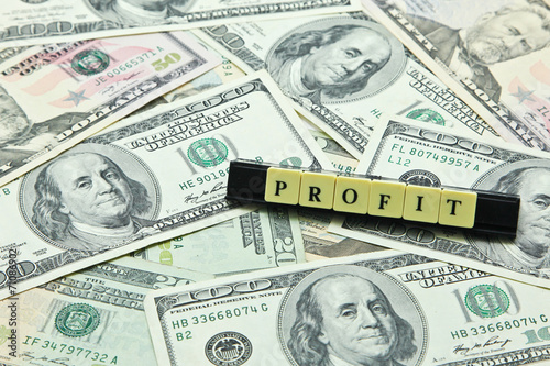 Word profit on pile of US dollar banknotes