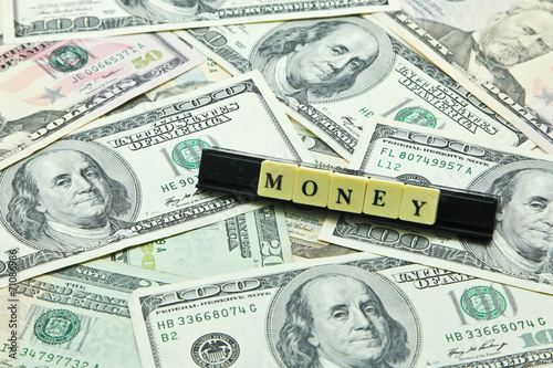 Word money on pile of US dollar banknotes