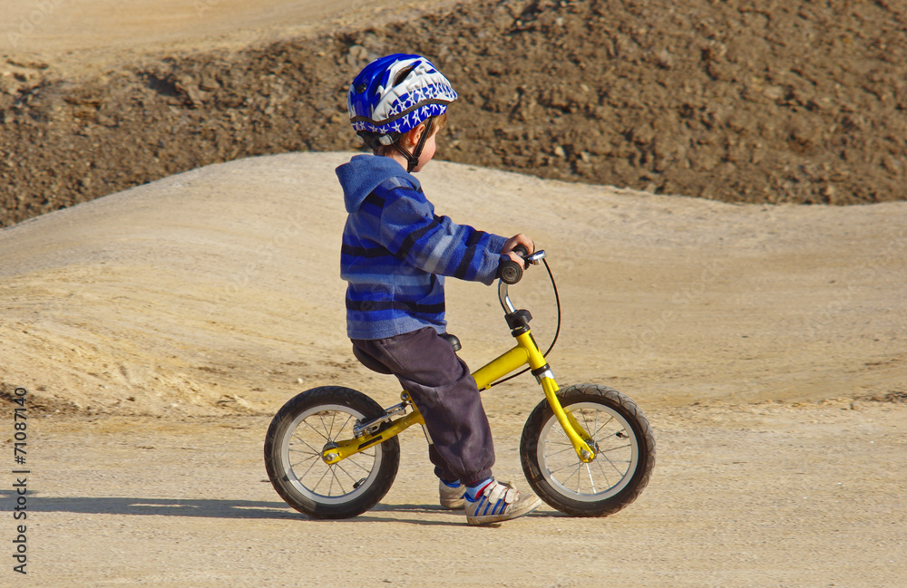 Little boy on a bicycle and wavy terrain in the background Little boy on a bicycle and wavy terrain in the background