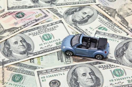 Car model on pile of US dollar banknotes