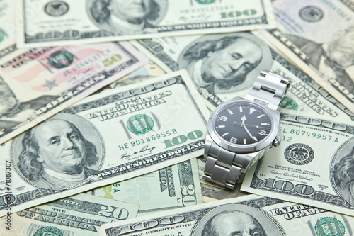Swiss watch on pile of US dollar banknotes